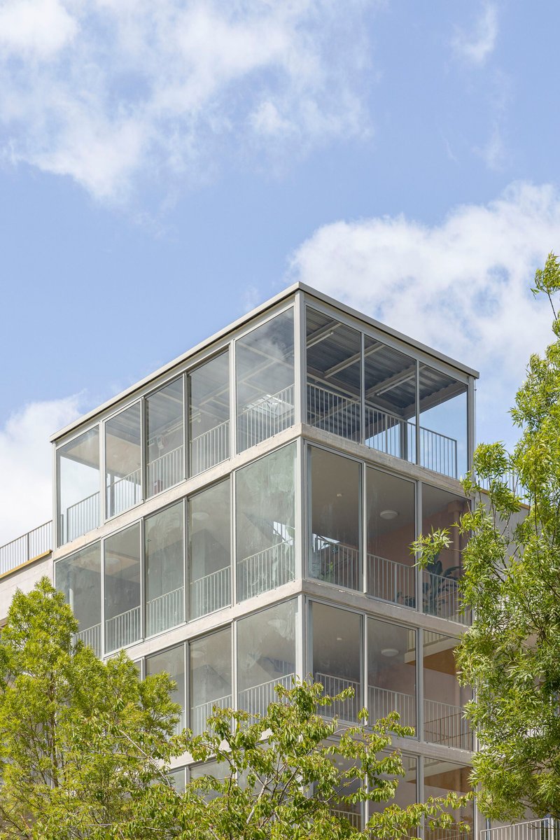 Upper floors of the glazed balcony stack with exposed ceiling slabs visible through transparent panels