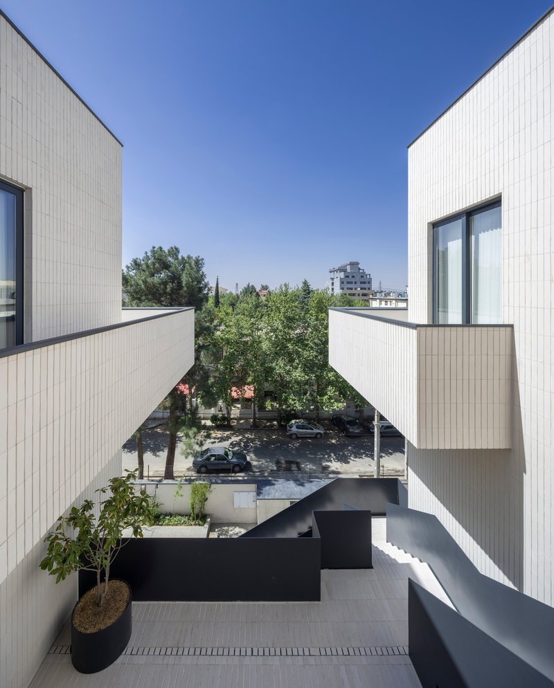 Rooftop terrace with cantilevered black steel walkways and white corrugated cladding overlooking a tree-lined street