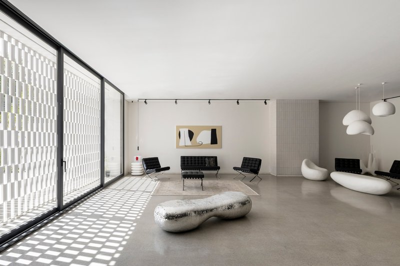 Interior living space with floor-to-ceiling glazing casting geometric shadow patterns across polished concrete floors