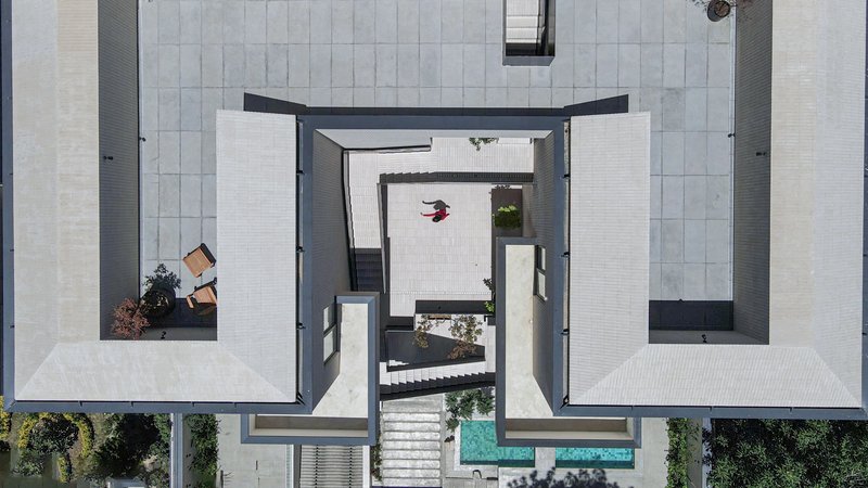 Overhead view of central stairwell with white stone paving, black metal stair volumes and turquoise pool edges