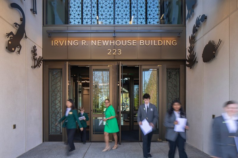 Bronze-framed glass doors with decorative metal panels and motion-blurred figures entering the lobby