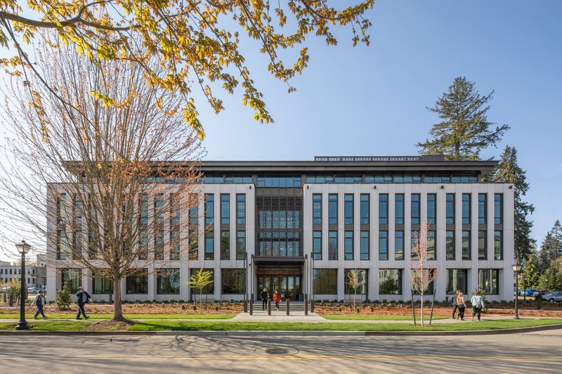 Street view of the colonnade facade with tall vertical fins framing a central patterned screen under bare spring trees