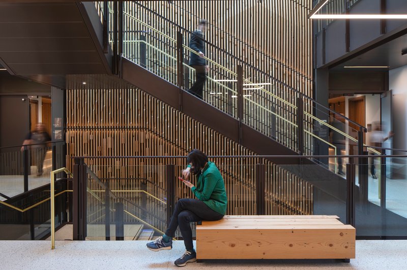 Steel staircase with timber bench seating against a vertical slatted wood screen wall