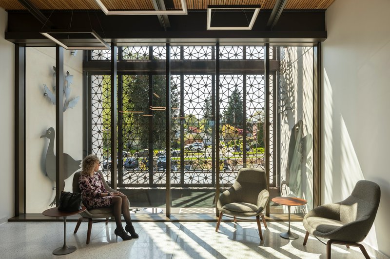Seating area with geometric metal screens filtering sunlight and casting shadows across the floor