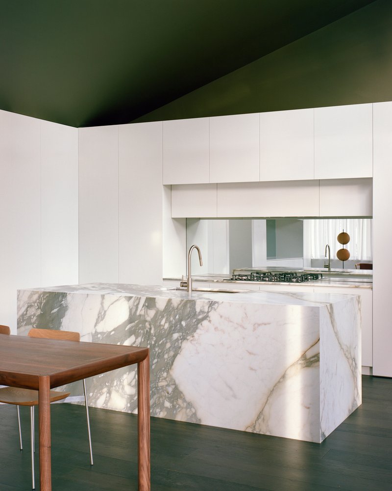 Close-up of the veined marble island and backsplash reflecting daylight from the window