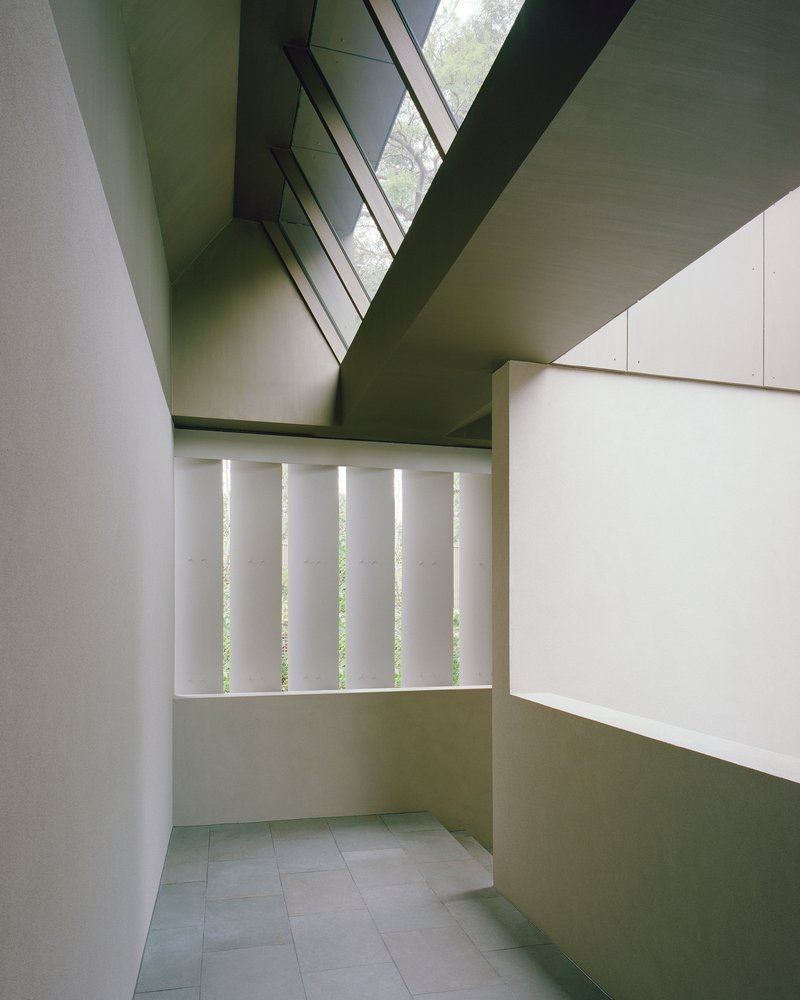 Interior corridor with vertical slot windows and clerestory glazing above white plaster walls