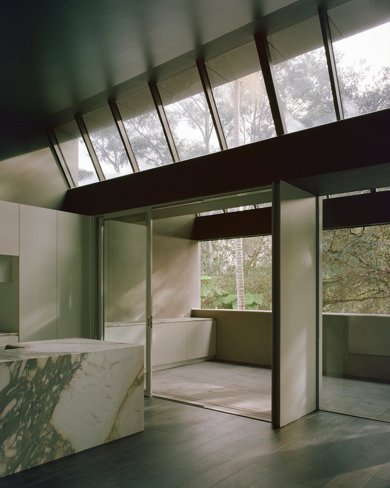 Interior living space with marble island beneath clerestory windows framing tree canopy views