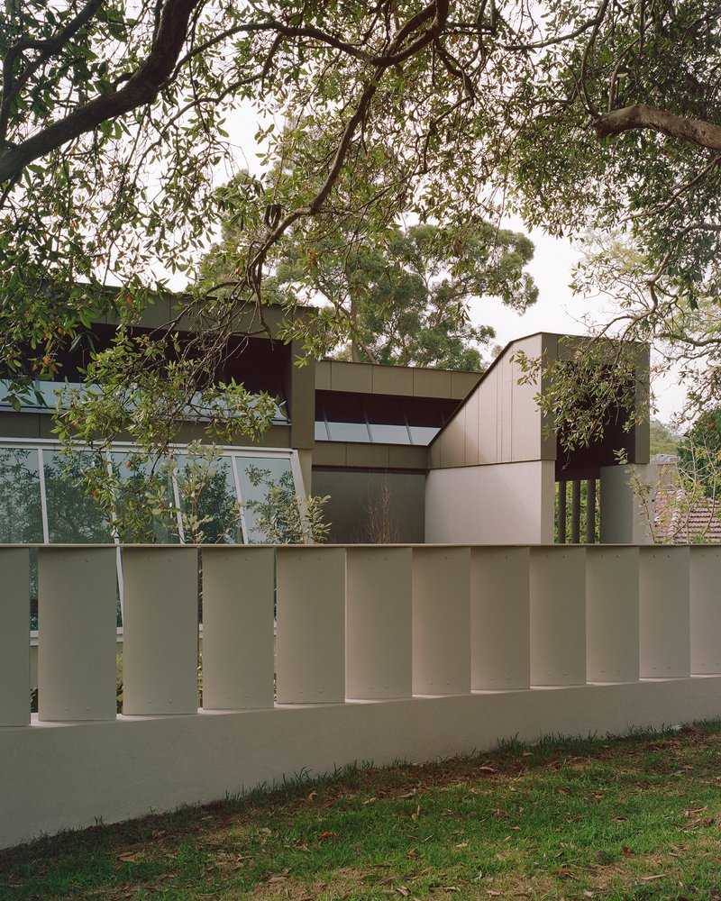 Vertical batten fence screening the residence from the street under mature eucalyptus trees