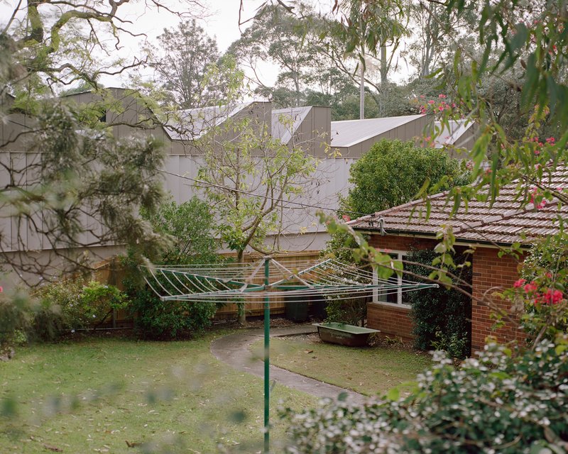 Garden courtyard with brick outbuilding and galvanized clothesline beneath the angled metal roofline