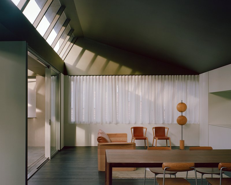 Living area with clerestory windows casting shadows across sheer curtains and timber furniture