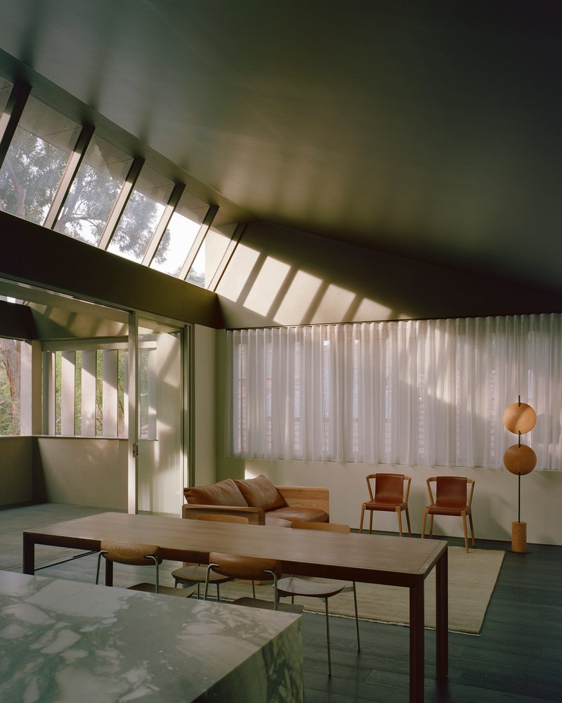 Angled clerestory windows above the dining space with light striping the green ceiling and walls