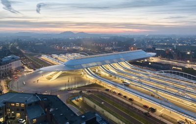 This architectural image showcases a modern train station at dusk, featuring a striking glass roof a