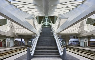 This architectural image showcases a modern train station with a striking design. The central stairc