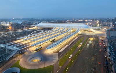 This architectural image showcases a modern train station at night, featuring a striking glass roof 