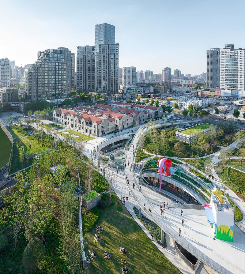 Elevated park with ribbon-like pathways and pedestrians crossing between planted berms in afternoon light