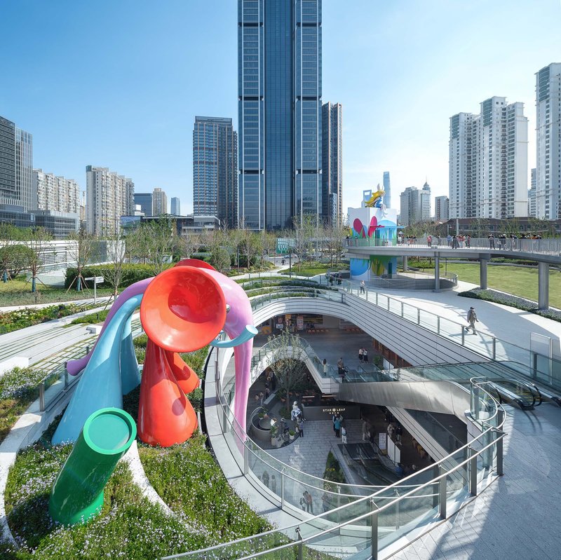 Colorful tubular sculpture rising from a planted terrace above a sunken glazed courtyard