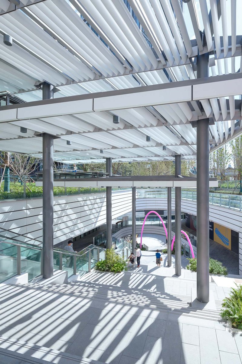 Upper terrace with horizontal cable railings and white louver canopy casting striped shadows in bright sunlight