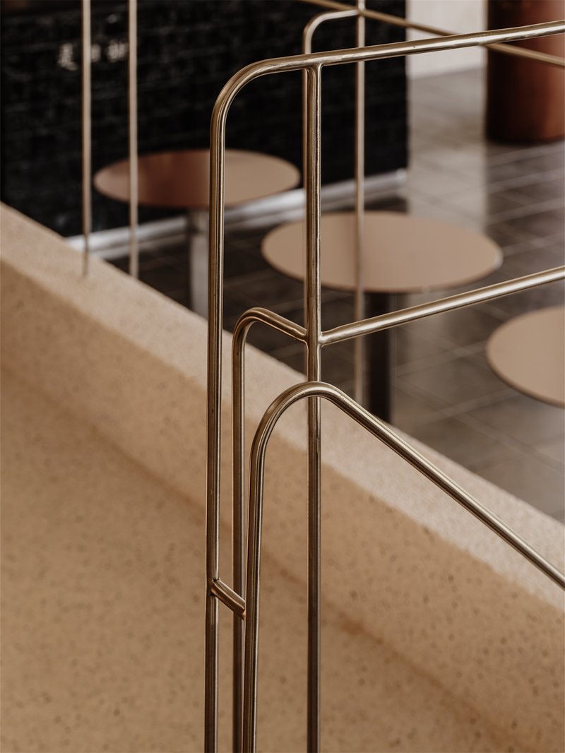 Detail of brass tubular railing anchored to terrazzo edge with curved corner joinery