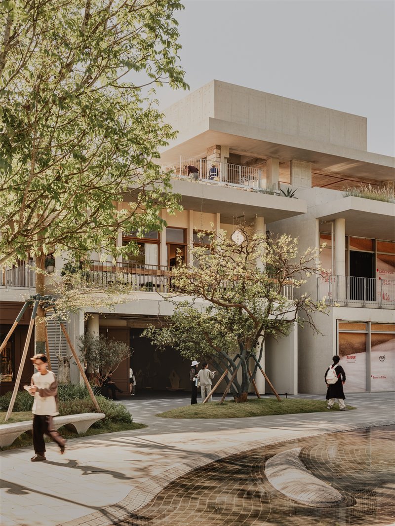 Street view of tiered concrete volumes with recessed balconies, trees, and pedestrians in foreground