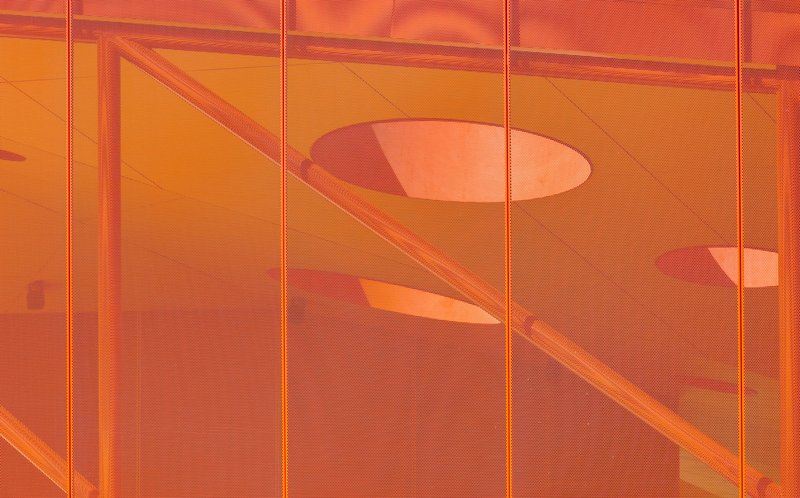 Translucent orange panel showing shadows of interior handrails and circular ceiling openings