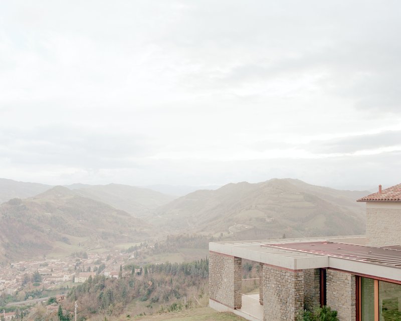 Flat roof terrace with timber battens overlooking a valley of distant hills in hazy light