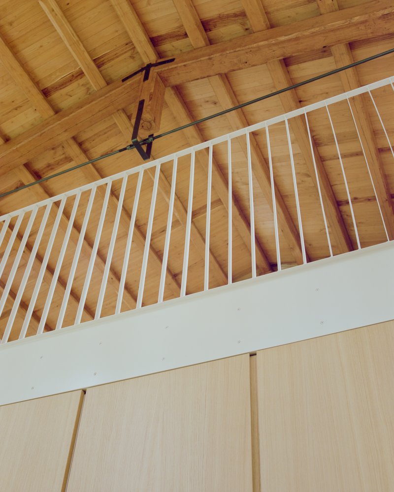 Upward view of the white metal railing against timber ceiling beams and planking