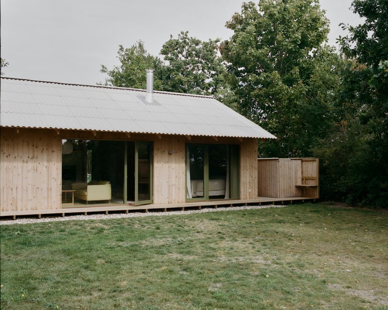 Corner view of timber pavilion with corrugated roof overhang and timber deck on gravel