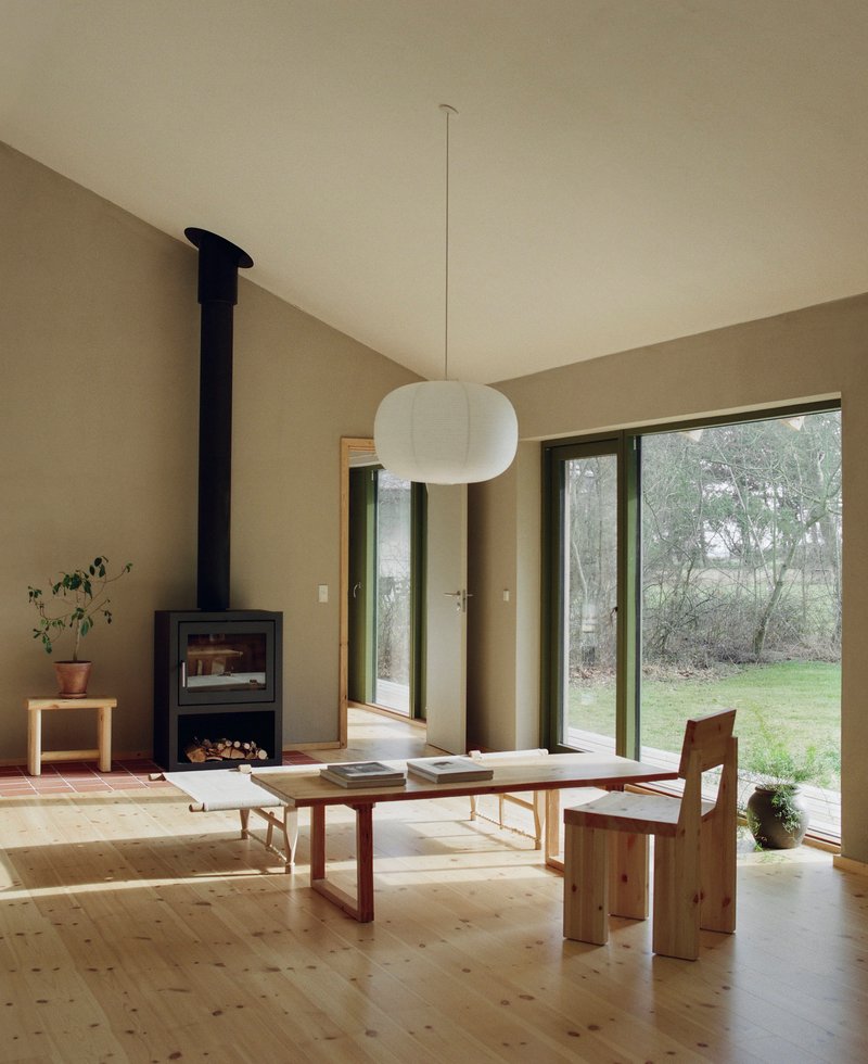 Living space with black wood stove, low table, and glass doors opening to garden
