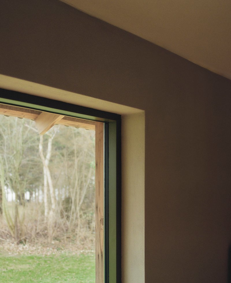 Detail of timber window frame with exposed plywood lining and view to winter trees