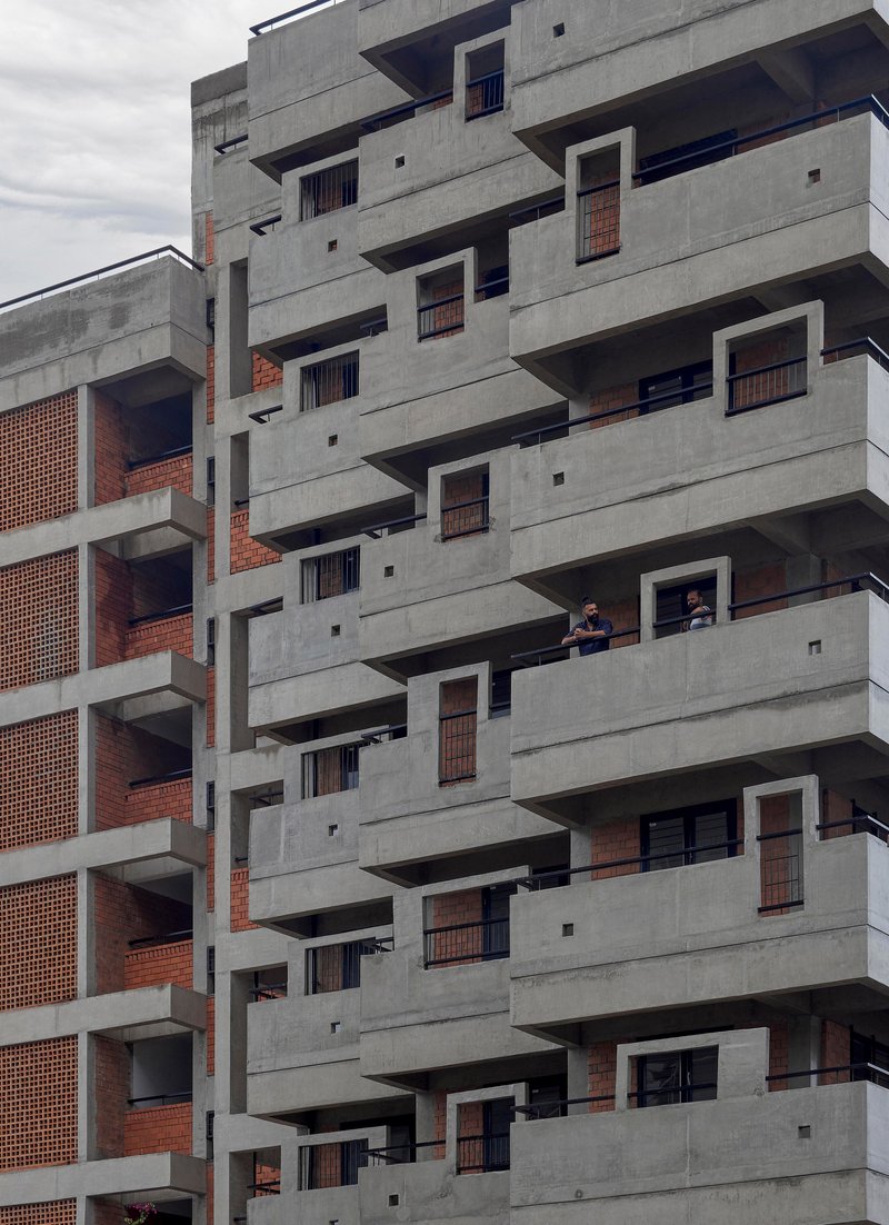 Stepped concrete balconies with brick screening and residents visible on one of the terraces