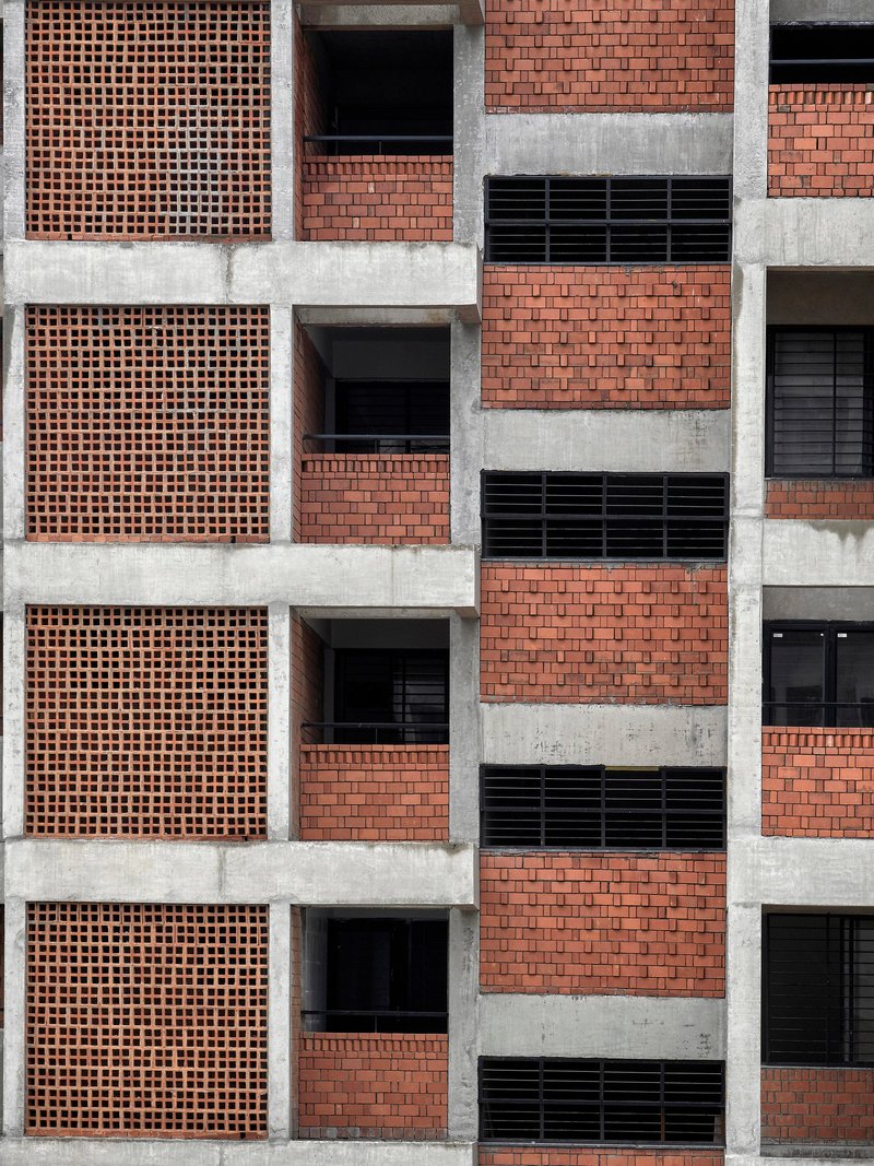 Flat frontal view of the gridded facade with terracotta brick screens and horizontal concrete bands