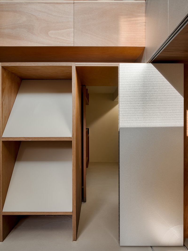 Close-up of angled plywood shelves with white laminate surfaces casting diagonal shadows