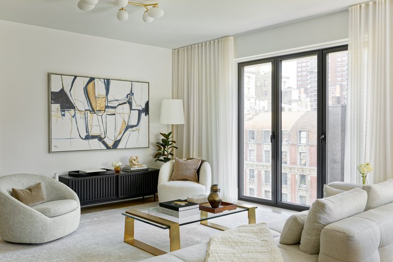 Living room with curved sofas and black-framed windows overlooking neighboring buildings