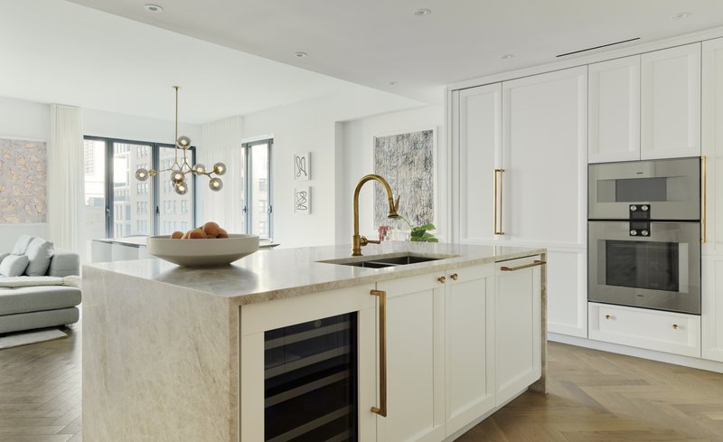 Open kitchen island with wine cooler and brass sink fixture overlooking adjacent living space