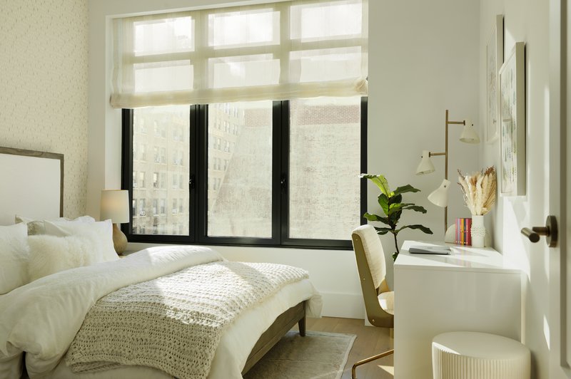 Bedroom with black-framed windows and built-in white desk beneath diffused natural light