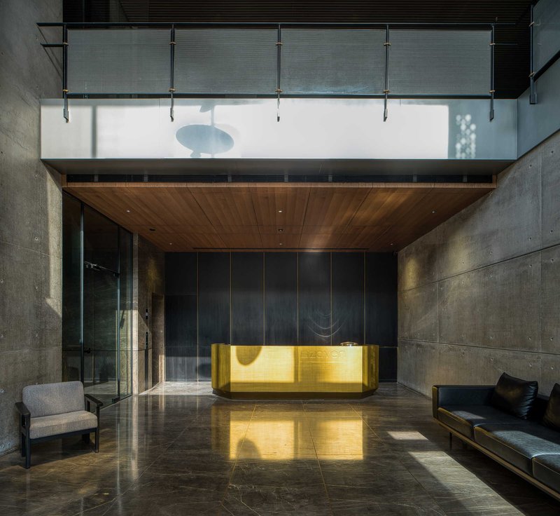Reception area featuring a brass-clad desk beneath a timber ceiling and glass mezzanine with cable railings