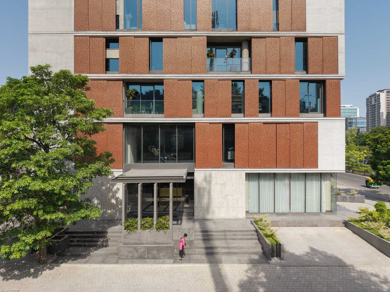 Elevated view of the stone and terracotta panel facade with a child walking across the entrance plaza