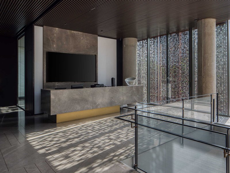 Interior lobby with perforated metal screen casting dappled shadows across polished stone floor and glass railings