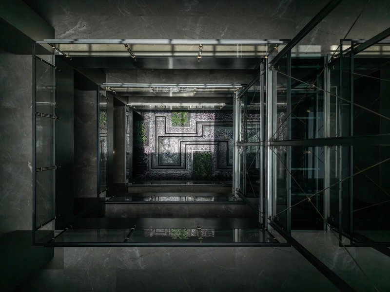 View up through glass-roofed central atrium with concrete structure and cascading planted terraces