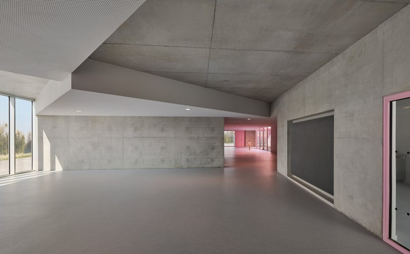 Concrete corridor with exposed ceiling and pink illuminated hallway receding into the distance