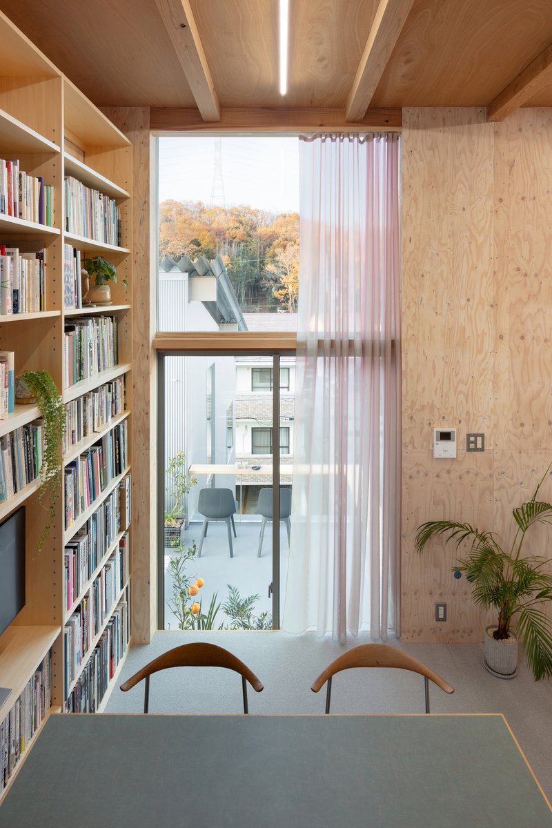 Study nook with floor-to-ceiling bookshelves and full-height window overlooking autumn foliage