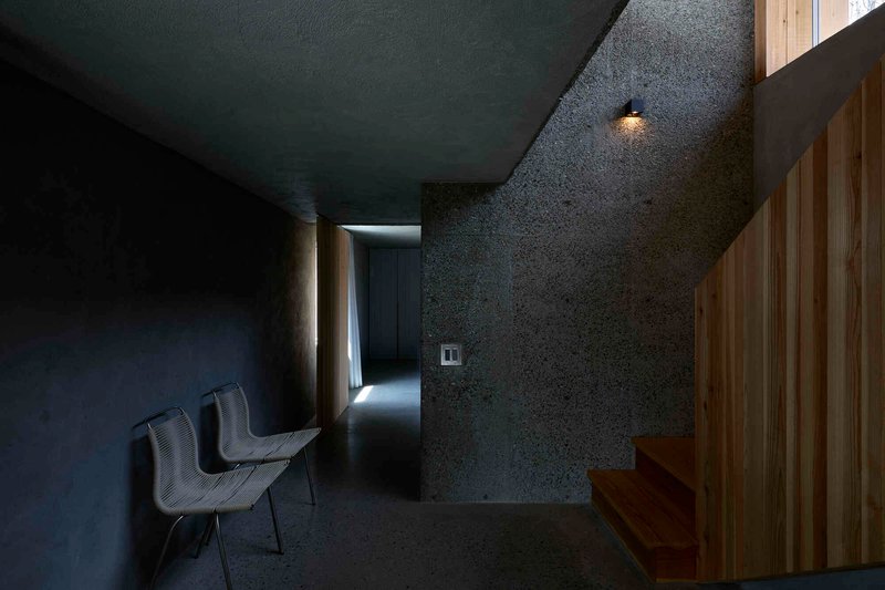 Dark textured concrete corridor with timber partition and recessed wall sconce