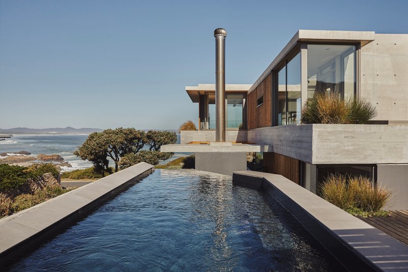 Infinity pool with concrete coping overlooking coastal vegetation and ocean views beyond