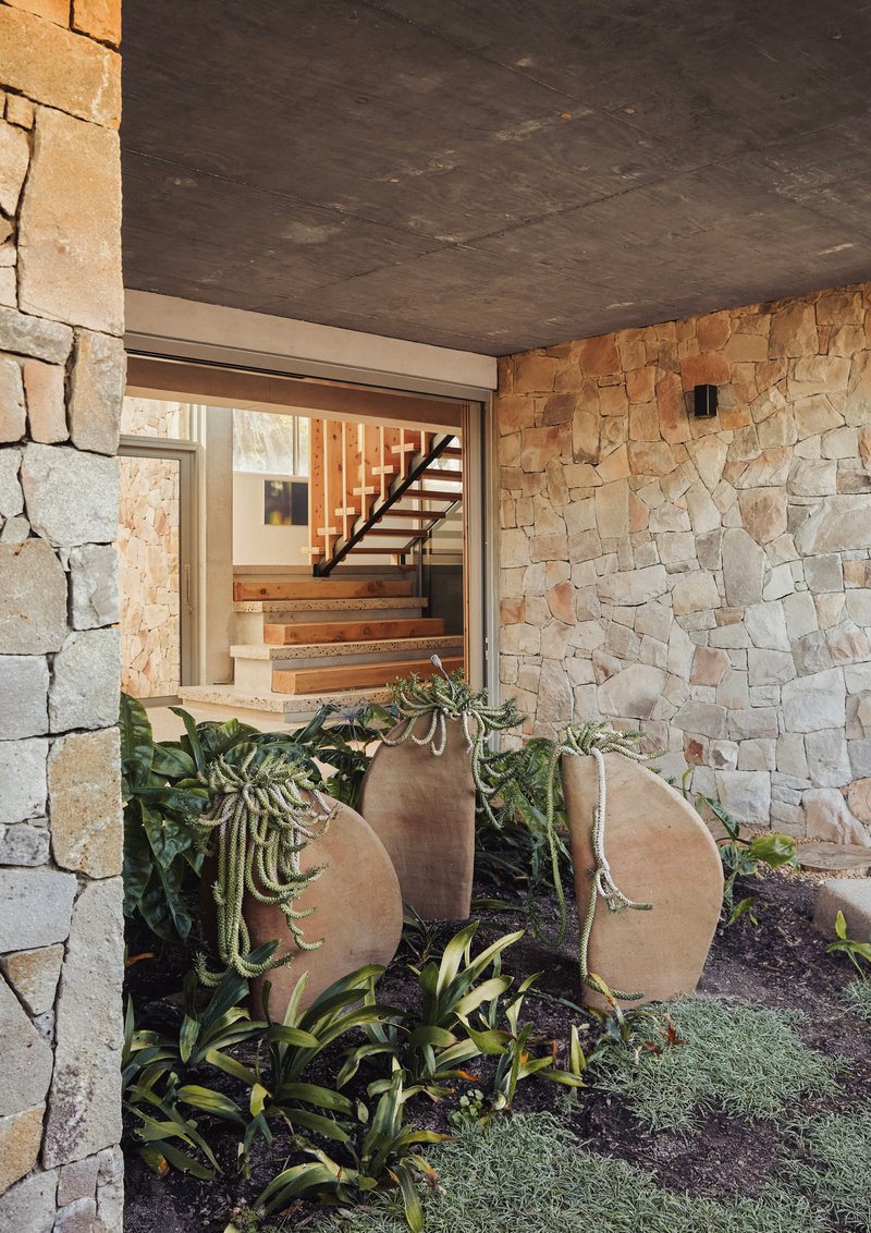 Entry courtyard with stone wall, planted bed with curved steel planters and cascading succulents