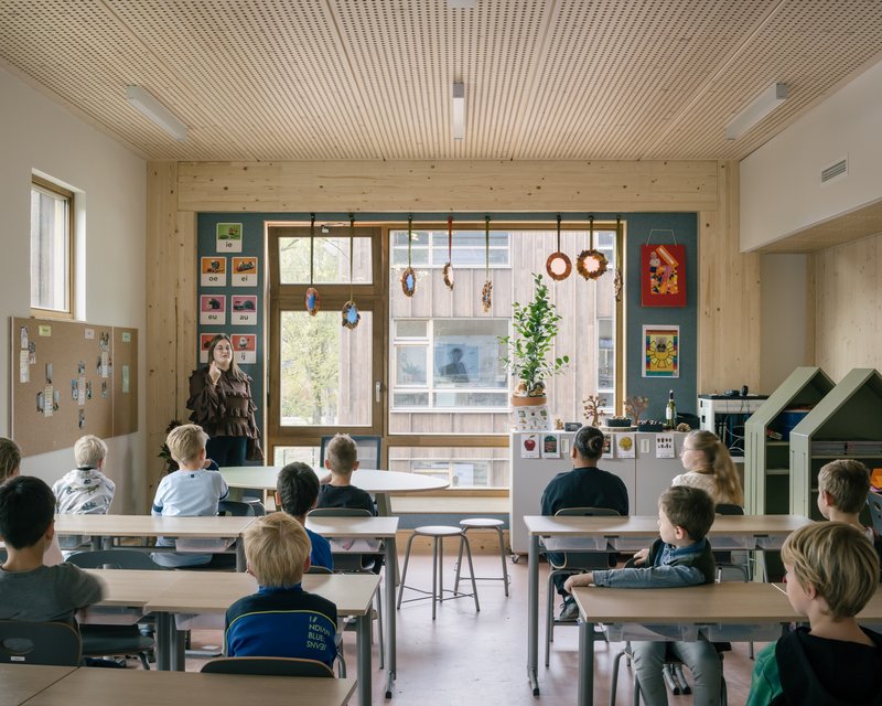 Classroom with timber slatted ceiling and students seated at desks facing a teacher by the window