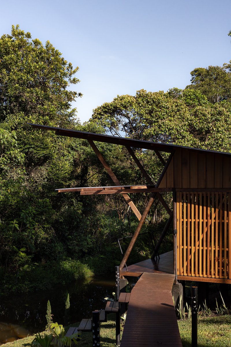 Exterior timber deck with diagonal structural bracing connecting the elevated volumes above the sloping lawn