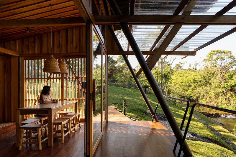 Timber dining space with vertical slat screens and glazed facade opening to sloped lawn