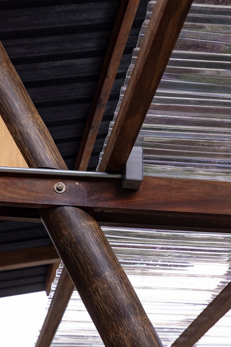 Detail of angled timber support beams and corrugated metal roofing with steel bracket connection