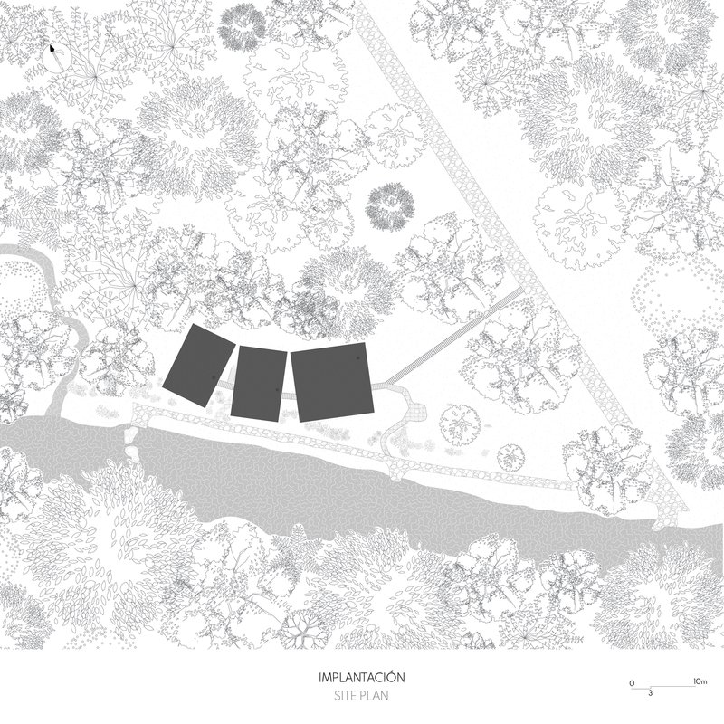 Site plan drawing showing three rectangular volumes positioned among trees near a curved shoreline