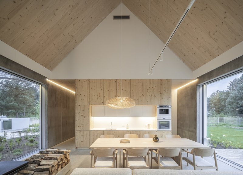 Dining area with exposed timber-plank ceiling and clerestory lighting over backlit kitchen wall